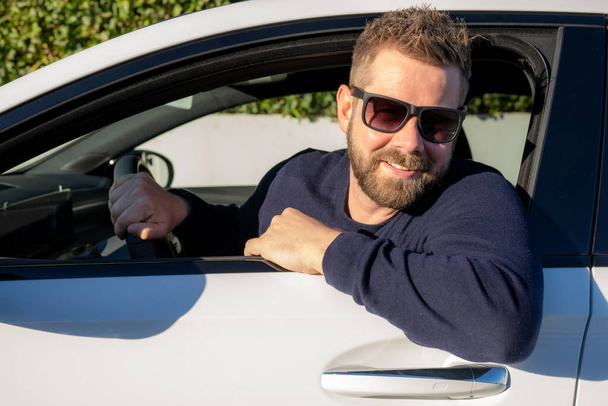 Schöner junger Mann im blauen Pullover am Steuer eines Autos - Foto, Bild