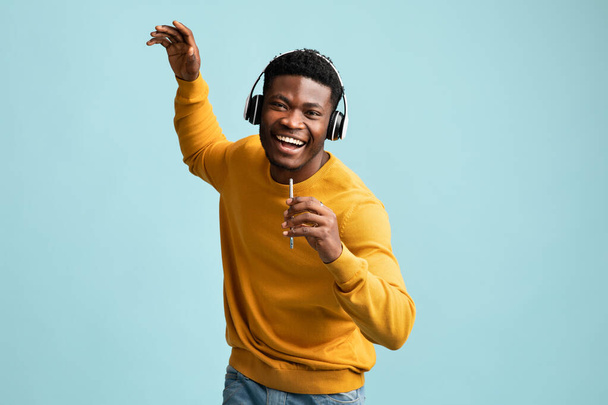 Knappe Afrikaans-Amerikaanse man met headset en smartphone zingen - Foto, afbeelding