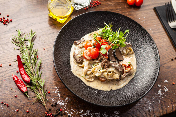 Black Angus beef tagliatelle pasta with fresh black truffles and parmegano. Delicious healthy traditional food closeup served for lunch in modern gourmet cuisine restaurant. - Photo, Image