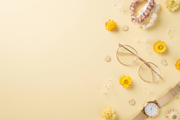 Top pohled fotografie ženské den složení stylové brýle scrunchies zlaté náramkové hodinky srdce a divoké květiny na izolované béžové pozadí s copyspace - Fotografie, Obrázek