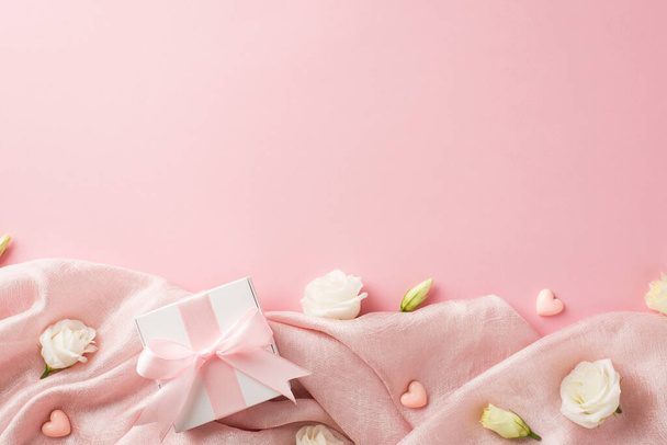 Top view fotó a női nap összetétele fehér ajándékdoboz rózsaszín selyem szalag íj kis szív és fehér préri gentian virág rügyek elszigetelt pasztell rózsaszín háttér üres hely - Fotó, kép