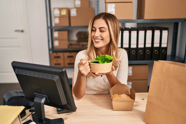 Junge blonde Frau E-Commerce-Kaufmann isst Salat im Büro - Foto, Bild