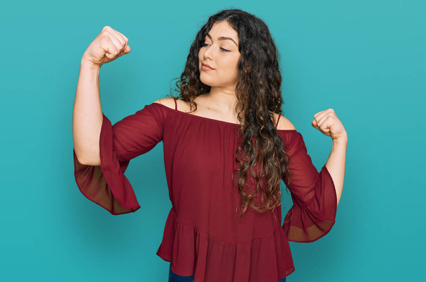 Joven chica hispana usando ropa casual mostrando los músculos de los brazos sonriendo orgullosa. concepto de fitness.  - Foto, Imagen