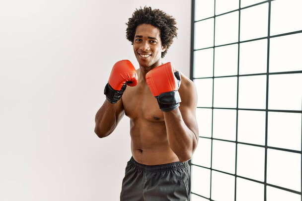 młody Afrykanin amerykański człowiek uśmiechnięty szczęśliwy boks na siłowni - Zdjęcie, obraz