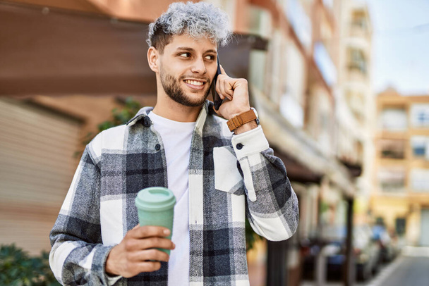Mladý hispánec mluví smartphone pití kávy ve městě. - Fotografie, Obrázek