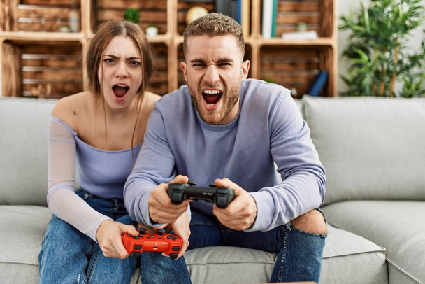 Mladý kavkazský pár křičí a hraje videohry doma. - Fotografie, Obrázek