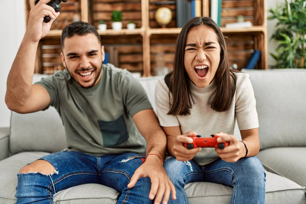 Νεαρό ζευγάρι Λατίνων απογοητευμένο παίζοντας βιντεοπαιχνίδι στο σπίτι. - Φωτογραφία, εικόνα