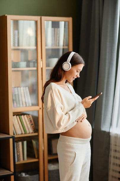 Femme enceinte écoutant de la musique avec téléphone portable - Photo, image