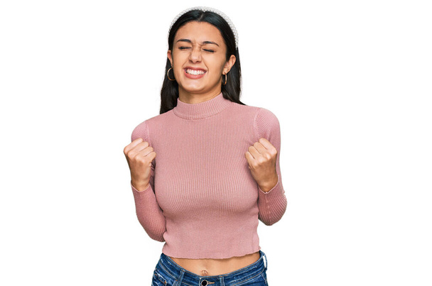 Young hispanic girl wearing casual clothes excited for success with arms raised and eyes closed celebrating victory smiling. winner concept.  - Foto, Bild