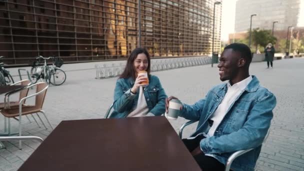 Χαρούμενο πολυεθνικό ζευγάρι πίνοντας καφέ στην πόλη - Πλάνα, βίντεο