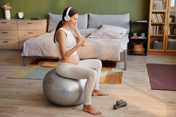 Pregnant woman exercising on fitness ball - Foto, afbeelding