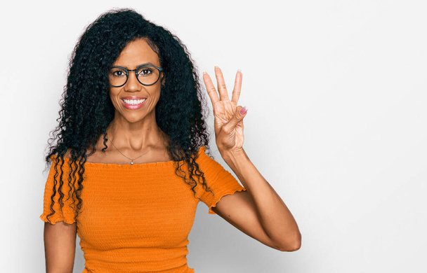 Middle age african american woman wearing casual clothes and glasses showing and pointing up with fingers number three while smiling confident and happy.  - Photo, Image