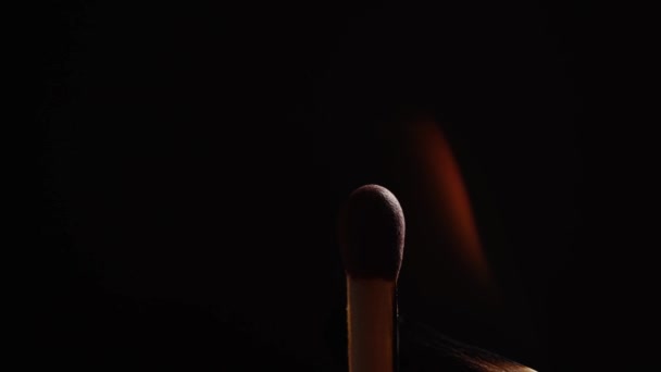 Persoon ontsteekt luciferstokje tegen zwarte achtergrond - Video