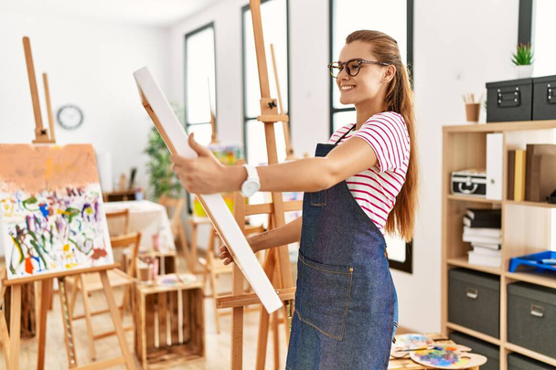 Mladá žena se usmívá sebevědomě drží plátno čerpat na výtvarné studio - Fotografie, Obrázek