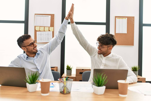 Two hispanic men business workers high five with hands raised up working at office - Fotó, kép