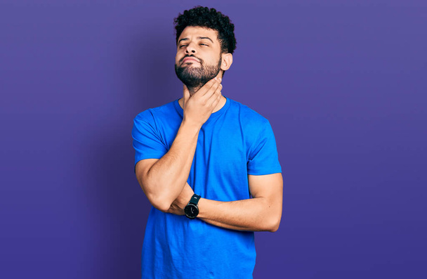 Young arab man with beard wearing casual blue t shirt touching painful neck, sore throat for flu, clod and infection  - Zdjęcie, obraz