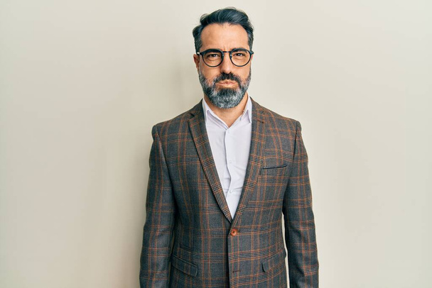 Middle age man with beard and grey hair wearing business jacket and glasses puffing cheeks with funny face. mouth inflated with air, crazy expression.  - Fotografie, Obrázek