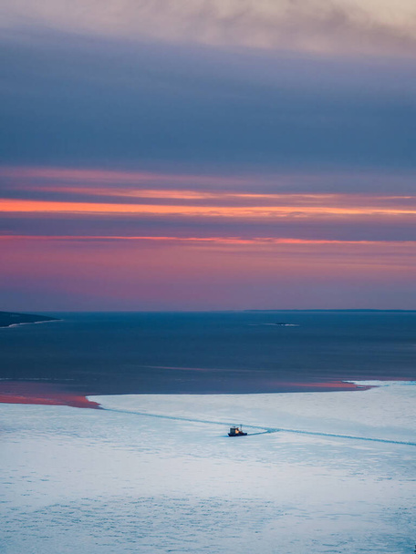 Далекий вид ледокола, раздавливающего лед. Научно-исследовательское судно пробивается сквозь лёд Белого моря. Вертикальный вид. - Фото, изображение