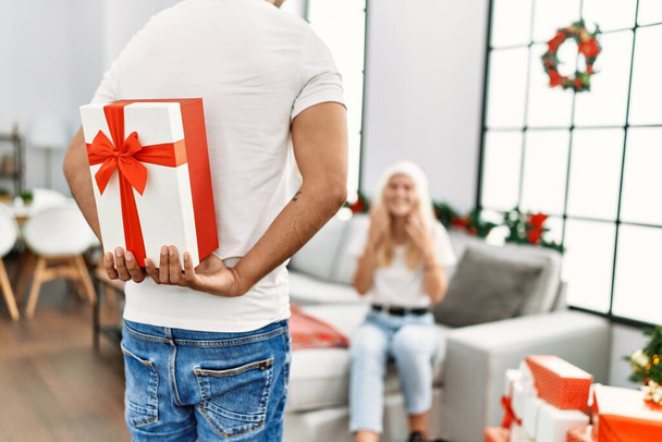 mężczyzna zaskakujące kobieta z Boże Narodzenie prezent w domu. - Zdjęcie, obraz