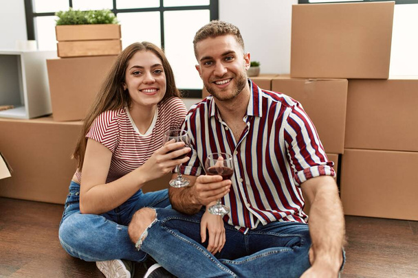 Young caucasian couple smiling happy toasting with red wine at new home - Foto, immagini