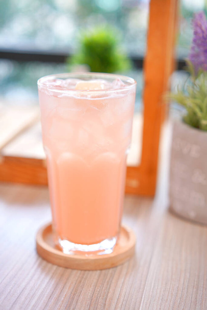Освежающий холодный напиток для лета на льду. Красочный летний напиток в высоком стекле с деревянной тарелкой для жаркого дня и вечеринки. - Фото, изображение