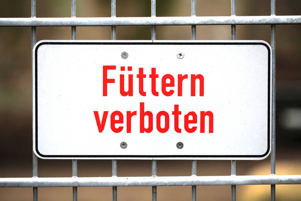Żelazny znak w zoo z niemieckimi słowami "Fuettern verboten" tłumaczy się na "Don 't feed" w języku angielskim - Zdjęcie, obraz