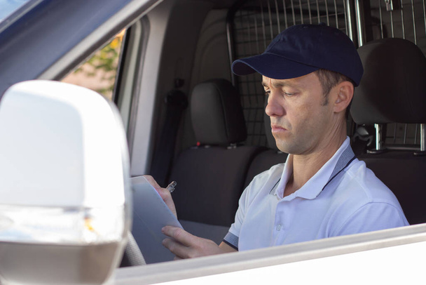 Skoncentrowany dostawca sprawdzający dokumenty w samochodzie - Zdjęcie, obraz