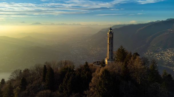 Drohnenaufnahme eines Leuchtturms über der Skyline des Comer Sees bei Sonnenuntergang - Faro Voltiano (Volta Leuchtturm) - Reiseziel, Brunate, Como, Lombardei, Italien - Foto, Bild