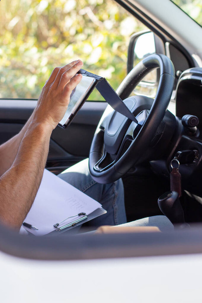 Close-up of deliveryman checking mobile phone in car - Photo, image