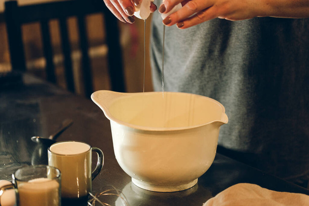 woman pouring milk into a pot on a kitchen table - Fotoğraf, Görsel