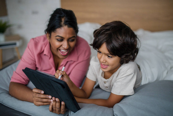 Indian mother using tablet with her little son and having fun at home. - Valokuva, kuva