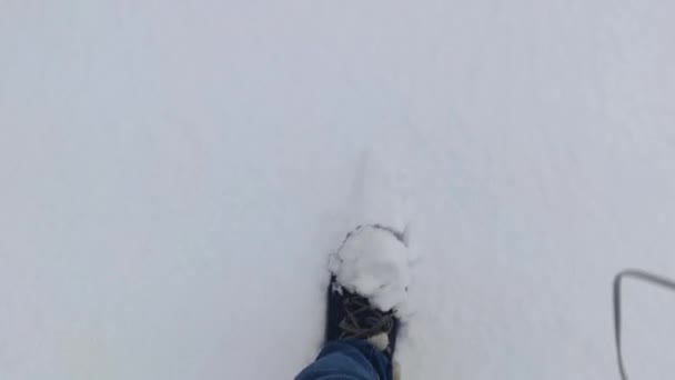 Kävele Lumikissa. Nainen patikoimassa syvässä lumessa talvella luonnossa. Jalat mies kävelee lumessa jalanjälkiä luminen päivä. Lepo- ja kausiluonteisuuden käsite. - Materiaali, video