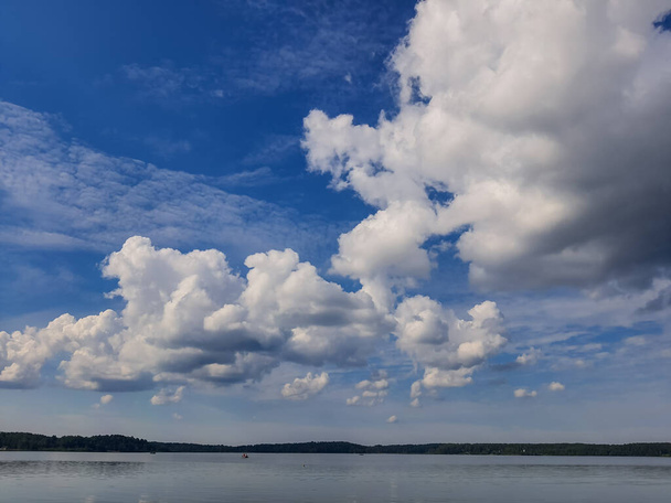 Il paesaggio marino nebbioso - la superficie dell'acqua calma del lago riflette il cielo. Le nubi di altocumulo sono piene di striature di bello di solito appaiono tra nuvole di strati inferiori e nubi di cirri superiori. - Foto, immagini