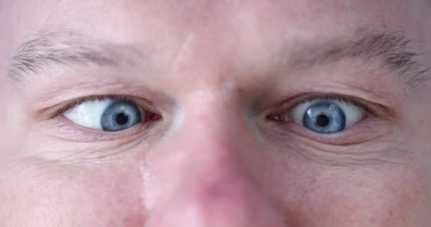 Vtipný mladý muž mžourá do očí a dívá se na svůj nos detailní 4k film - Záběry, video