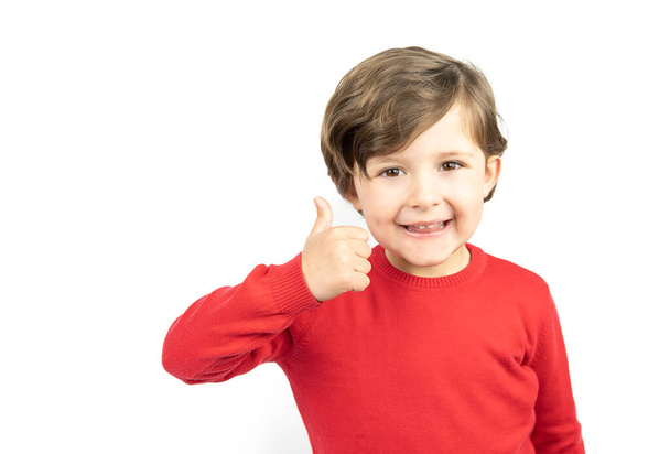 Счастливый мальчик на белом фоне с большим пальцем на руке. Успех, позитивное отношение, согласие. - Фото, изображение