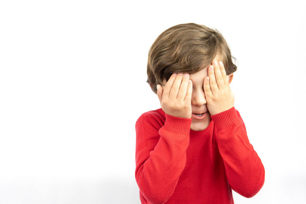 Little boy closing hid eyes by hand isolated over white background. - Photo, Image