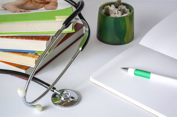 Arzt- oder Studententisch mit Stethoskop, Notizblock, Büchern. Medizinische Aus- oder Weiterbildung. Mit Kopierraum - Foto, Bild