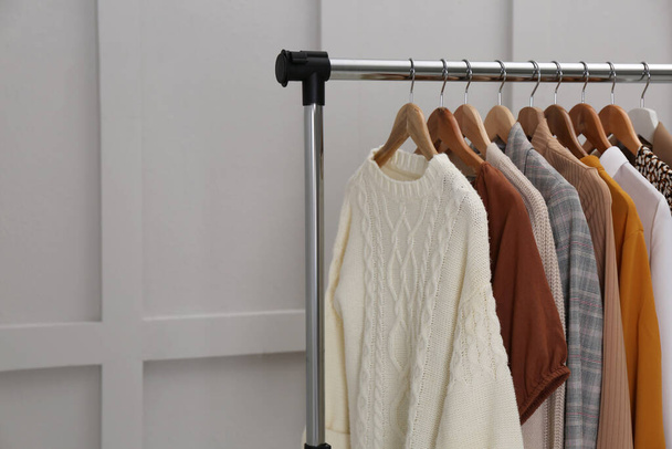 Rack with different stylish clothes near grey wall. Space for text - Φωτογραφία, εικόνα