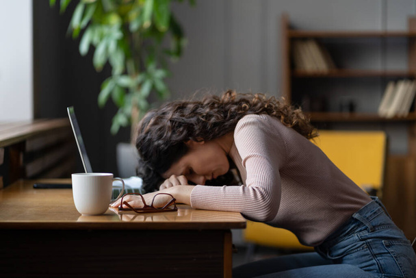 Перероблена втомлена фрілансерка або віддалений працівник спить на столі з ноутбуком страждає від втоми
 - Фото, зображення