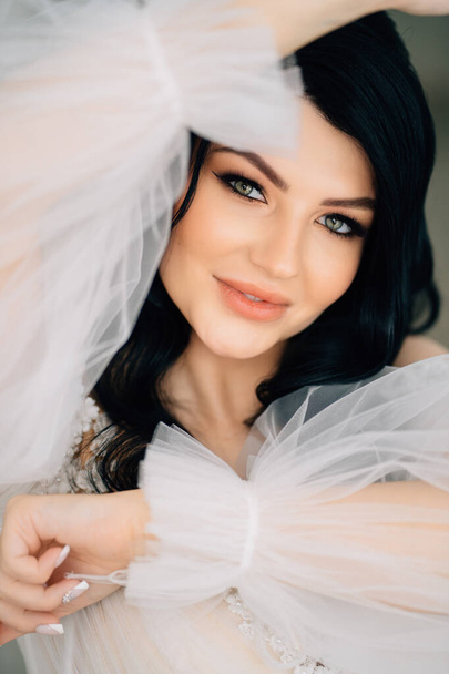 close-up. beautiful brunette bride in white dress with transparent puffy sleeves - Fotografie, Obrázek