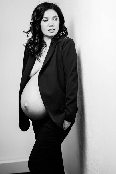 a beautiful pregnant woman in a black jacket with bare breasts and a belly - Foto, immagini