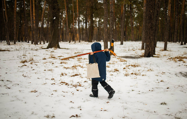 Bambino che cammina con bastone da hockey nella foresta invernale, bambino, sport, concetto di azione. - Foto, immagini