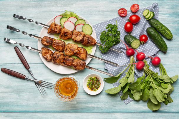 Appetizing caseiro shish kebab, fatias e legumes inteiros, um copo de vinho vista superior sobre um fundo de madeira azul. - Foto, Imagem