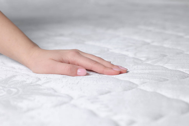 Woman touching soft white mattress, closeup view - 写真・画像