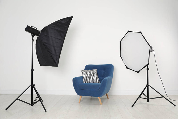 Comfortable armchair and professional lighting equipment in photo studio - Foto, Imagem