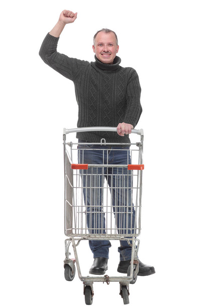 Full length portrait of a man posing next to an empty shopping cart with hand up - Fotografie, Obrázek