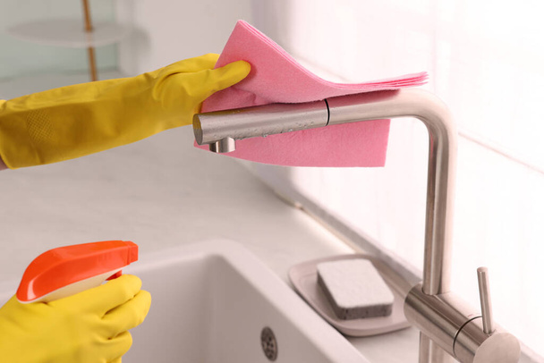 Woman cleaning faucet with rag and detergent in kitchen, closeup - Foto, immagini