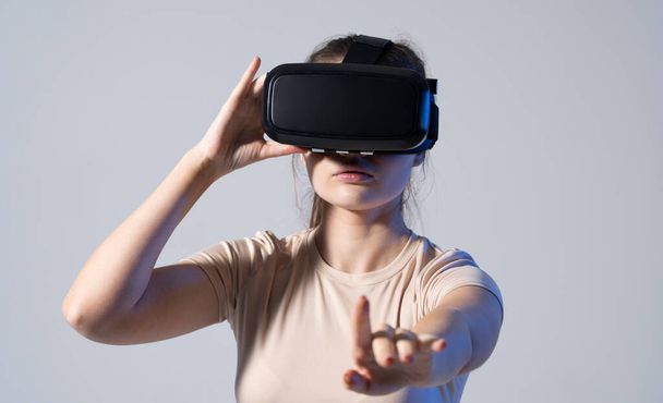 Close up of young woman stands in studio wearing VR glasses and swiping scrolling with hands in air. Virtual reality technology. - Foto, Imagem