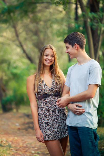 Guy schaut sein geliebtes lachendes Mädchen an. Fürsorglicher junger Mann hält die Hand eines minderjährigen Geliebten im Park - Foto, Bild