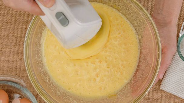 ビスケットベースのレシピでアップルケーキ,ステップバイステップのベーキングプロセス.卵と砂糖をガラスボウルに入れ、フラットレイアウトのミックス。台所のテーブルの上に食材を閉じます - 写真・画像